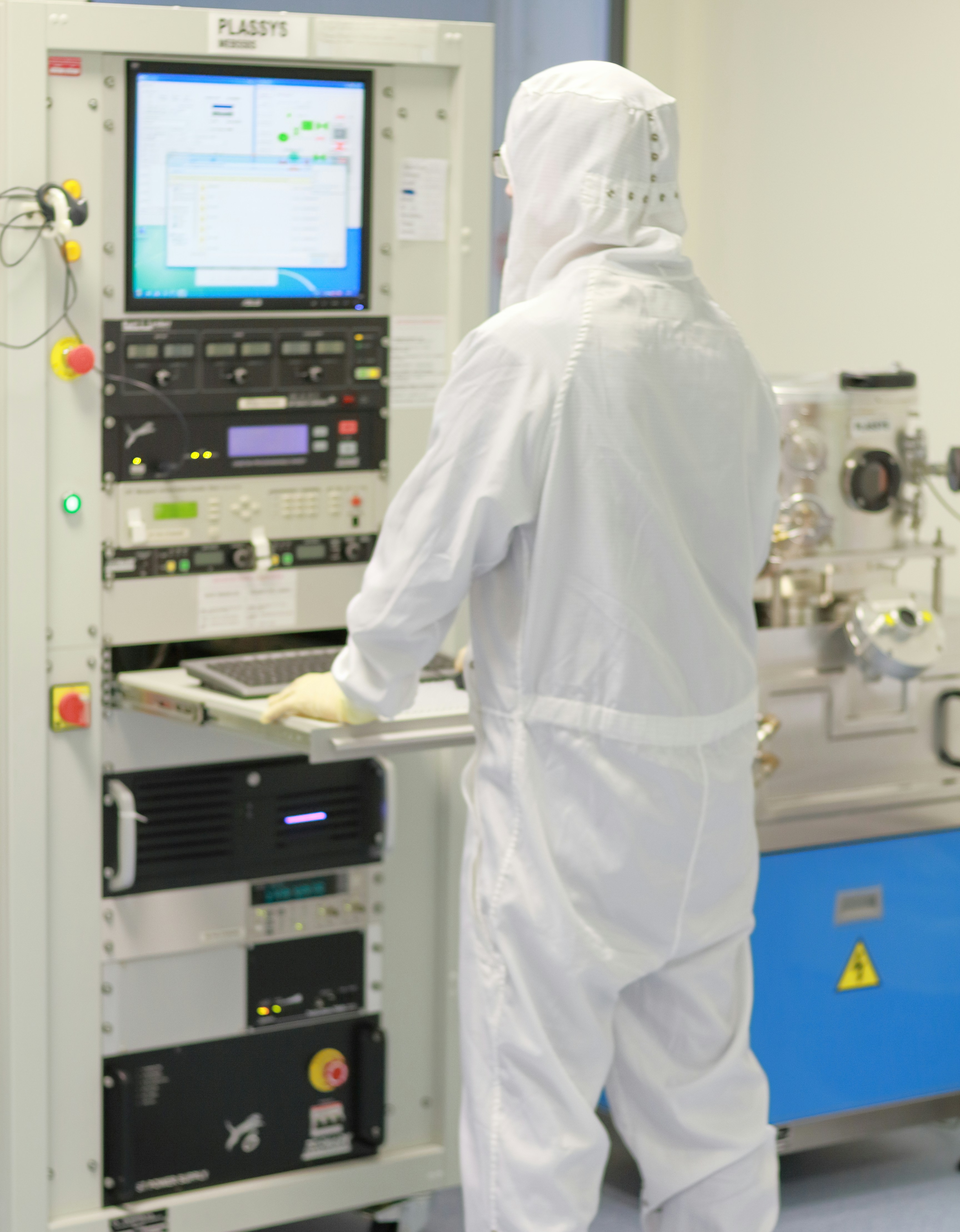 Gowned cleanroom workers in full protective suits inside semiconductor fab